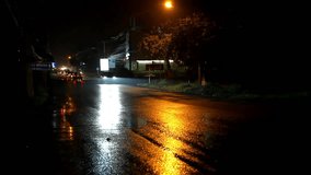 Cars and motorbikes driving on a wet road at night after rain. Video