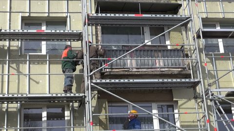 LITHUANIA, PANEVEZYS DISTRICT – APRIL 17, 2014: workers fixing thermal insulation material rock wool on house wall, April 17, 2014