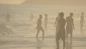 Silhouettes of carioca Brazilians playing altinho futebol beach football kicking soccer balls in the waves Ipanema Beach Rio de Janeiro
