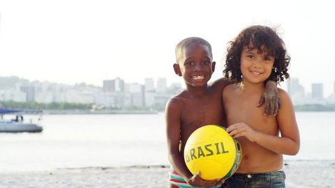 Kids pose and smile with a soccer ball on a beach