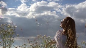 Happy girl with long hair having fun outdoor. Beauty girl spinning, laughing and catching soap bubbles. Countryside. Nature. Freedom. Slow motion video footage 1080p full HD. High speed camera shot