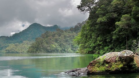 White clouds and grey clouds moving over tropical lake, mountains and forest in the Philippines