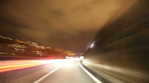 HD timelapse of car driving on highway at night through tunnels.