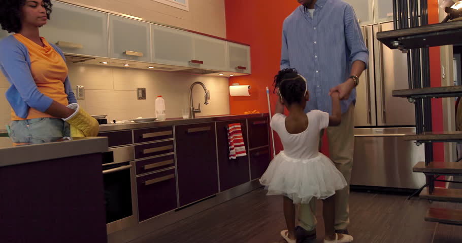 Little African American Girl Dances with her Parents int he kitchen