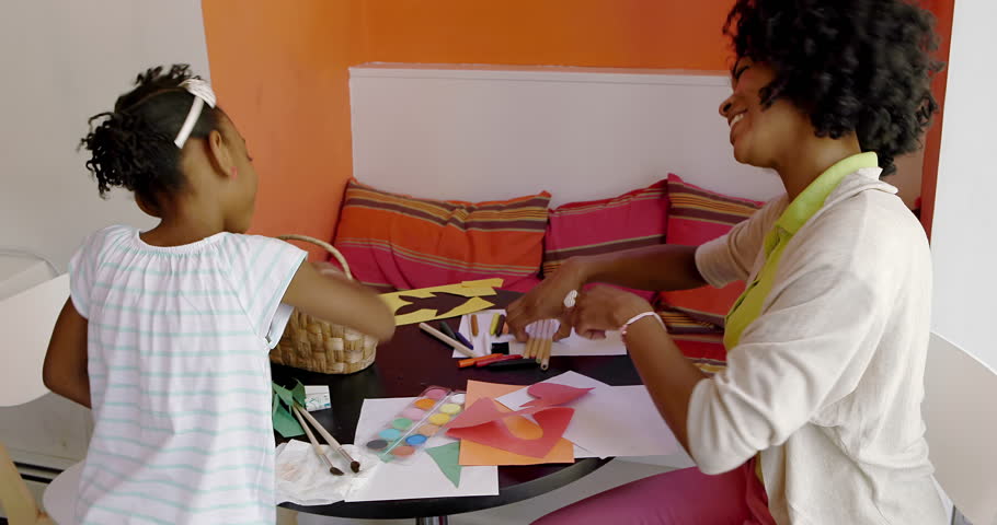 African American Mother and Daughter sit and the kitchen table doing arts and crafts and homework together. | Shutterstock HD Video #6686774