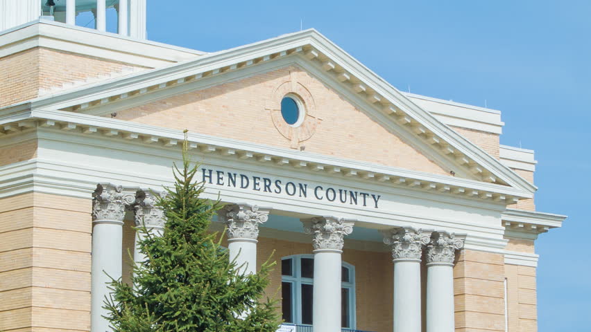 Close-up of the Old Henderson County Court House situated on Main Street of Historic Downtown Hendersonville, NC. Featured with a Blue Sky Background and a Green Tree in the Foreground.