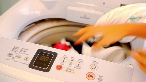 Girl hands puts dirty clothes in the washing machine. Video macro 1920x1080