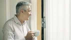 pensive man drinking hot tea at the window: coffee, beverage, steaming, look