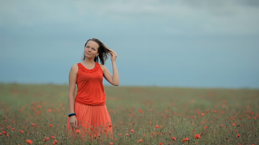 Nice young pretty girl in red bright dress laugh in the poppy field