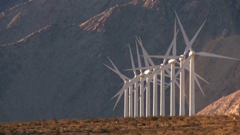 Rows of wind turbines producing clean alternative energy in barren landscape
