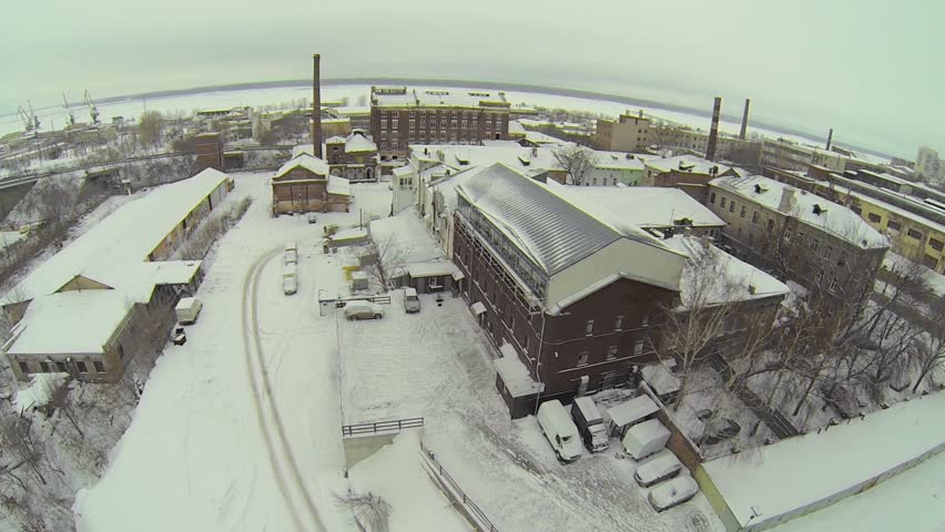Car traffic on road among industrial buildings at winter day. Aerial view