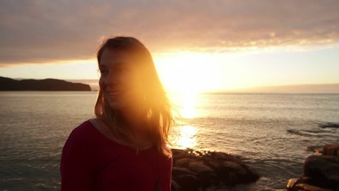 Smiling girl beside the ocean and rising sun, close up, atmospheric, a new day.