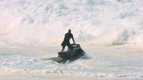 Dramatic shot of lifeguard launching rescue jet-ski into crashing giant waves 60 FPS