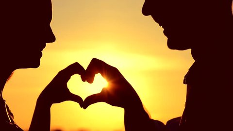 Sun in hands. Beauty Girl and her Handsome Boyfriend making shape of Heart by their Hands against beautiful sunset on horizon. Love. Nature. Vacation. Hope. Freedom, hippie generation. Full HD 1080
