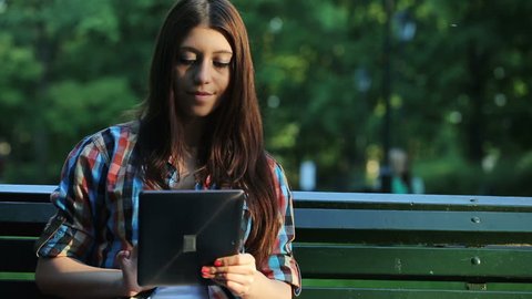 Happy young teenager with tablet computer in the park
