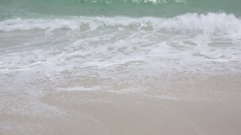 Medium shot of waves breaking on the sand.