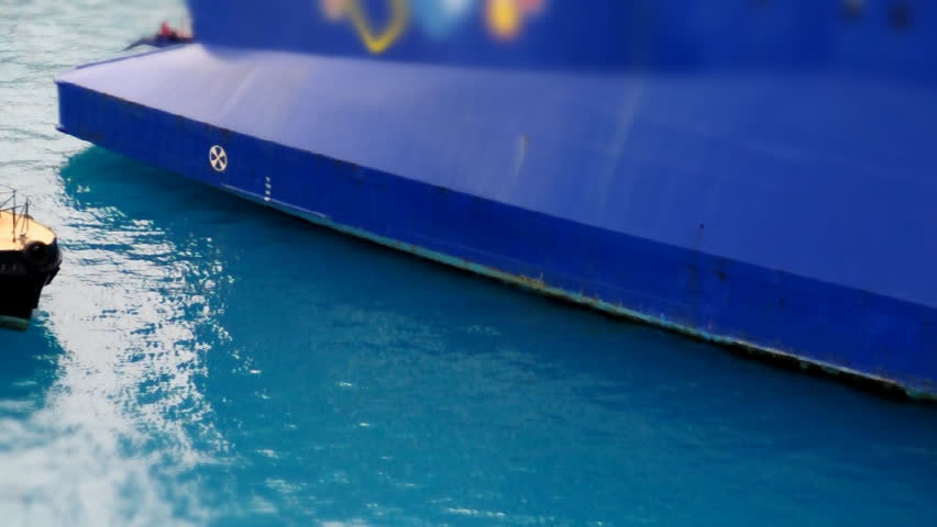 A tug boat travels past a large cruise ship in Nassau.