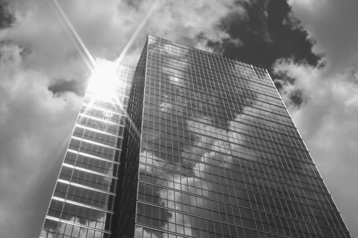 Timelapse office tower. Sun and clouds reflected in windows. Black and white.