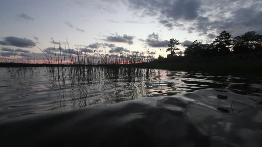 Zoomed in video of Georgian Bay water at sunset.  Cloudy sky and trees in cottage country