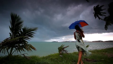 young woman on a tropical beach with umbrella in rainy season. Video Koh Samui