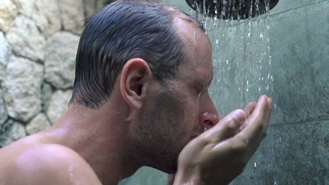 Young man washing face under shower, super slow motion, shot at 240fps
