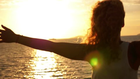 Young Happy Girl with Curly Hair and Tatto Spreading Arms at Beautiful Sunset. Sailing on the Ferry. Motivating Inspiring Slow Motion Video.