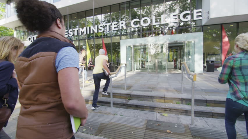 Cheerful student group entering college building on a sunny autumn day