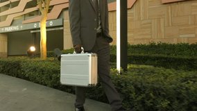 Steadicam shot of African American business man walking with  silver brief case in the city. 