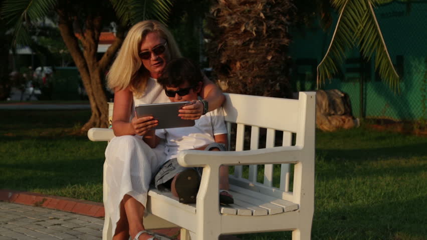 Mother and son using digital tablet in park 