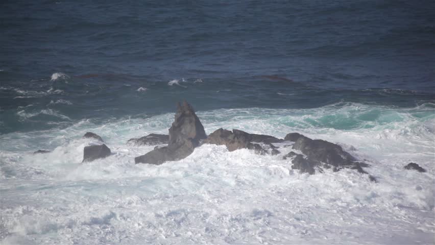 Waves crash over rocks in Pacific Ocean.