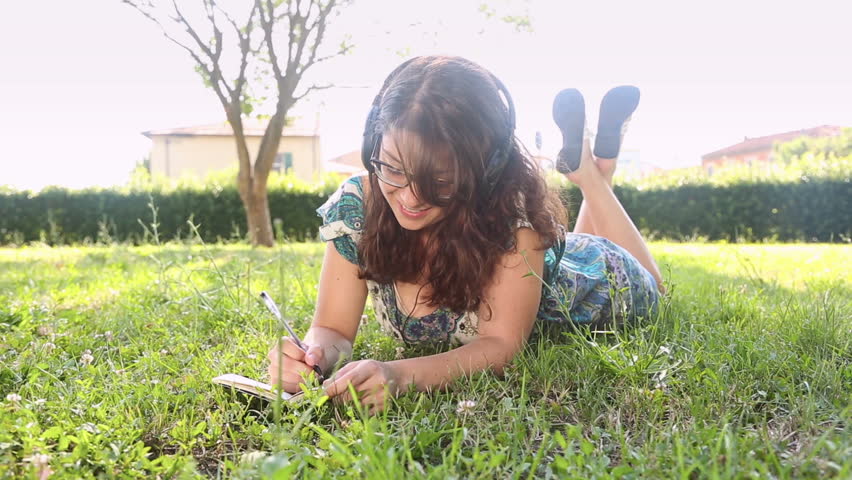 Beautiful Young Woman at Park Writing on Notepad
