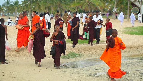 People in orange clothes on the beach among palm.Shri Lanka, Kalkudah, March 20, 2014