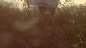 Beauty Girl on summer field dreaming. Beautiful young woman over cloudy sky enjoying nature and smelling wild flowers. Slow motion video footage full HD 1080. High speed camera shot 240 fps