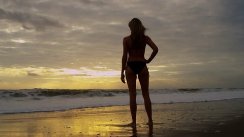 Young Caucasian female wearing bikini enjoying healthy outdoor lifestyle sunrise beach vacation jumping joy silhouette shot on RED EPIC
