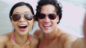 Attractive young Asian Chinese couple head shoulders portrait having fun swimwear beach smiling to camera filming social media video self portrait full frame shot on RED EPIC