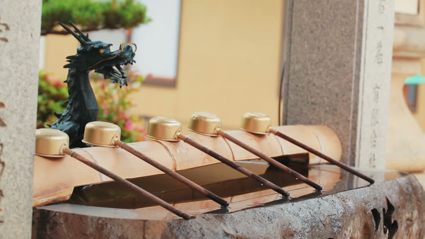Young Woman washing her hands at a traditional Japanese shrine