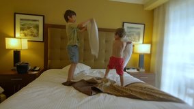 Two boys having a pillow fight on a king size bed. slow motion video clip