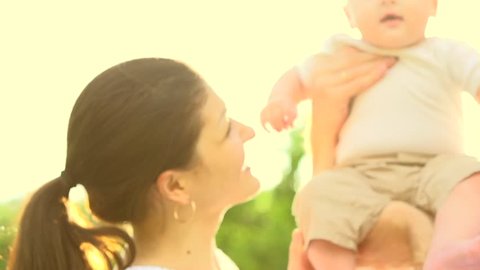 Happy family with little baby outdoors. Mother, Father and Baby having fun Together in Green Summer Park. Mom, Dad and Child. Happy smiling Family enjoying nature. Slow motion 1080p. High speed camera