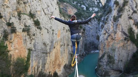 France, 2013. A woman tightrope walking over high canyon lost her balance and hangs from the rope.
