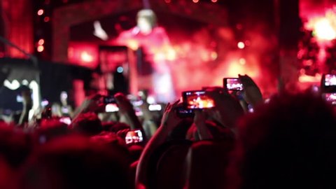 Euphoric crowd making a video and photo with smartphone and tablet.