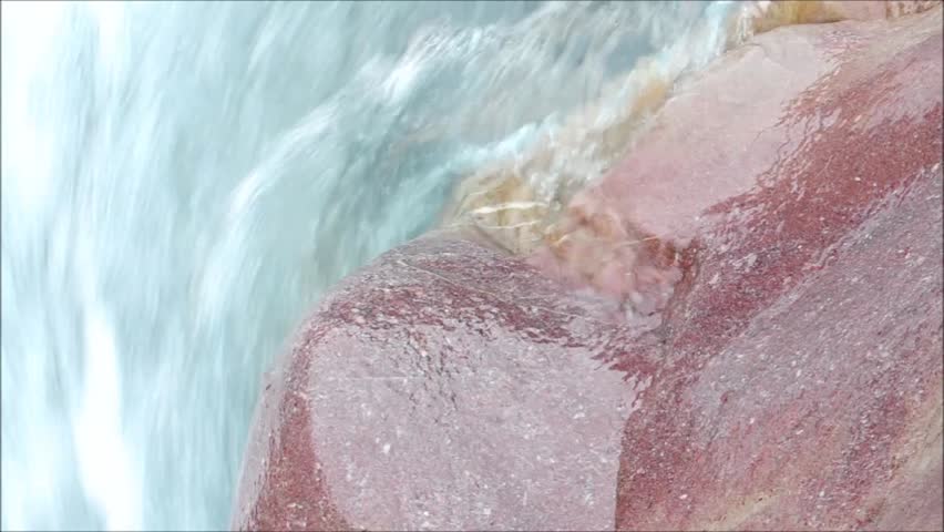closeup of Red Stone beside fast streaming Mountain River