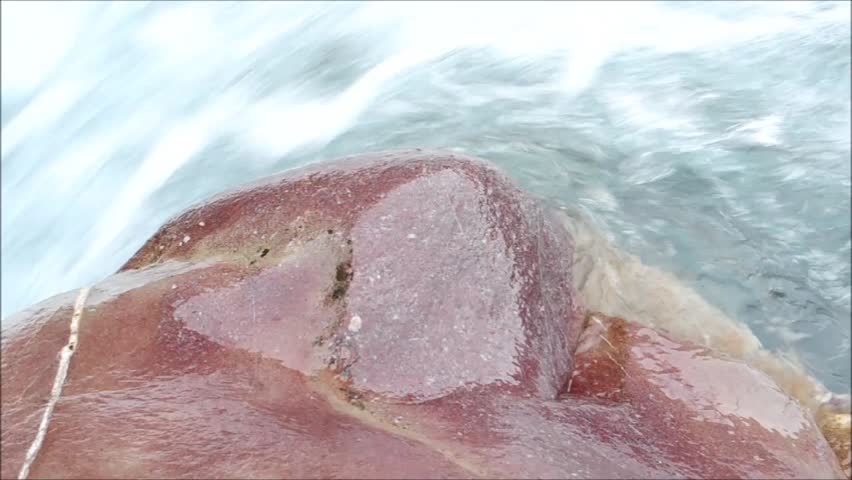 closeup of Red Stone beside fast streaming Mountain River