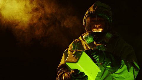 A man dressed in military grade hazmat protective garb uses a Geiger counter to evaluate possible radioactivity in the area.