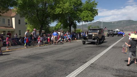 MORONI, UTAH - JUL 2014: Patriotic parade important to citizens of small rural America. Rural community parade kids and candy fast time lapse. Historic car, tractors, and trucks are main attraction.