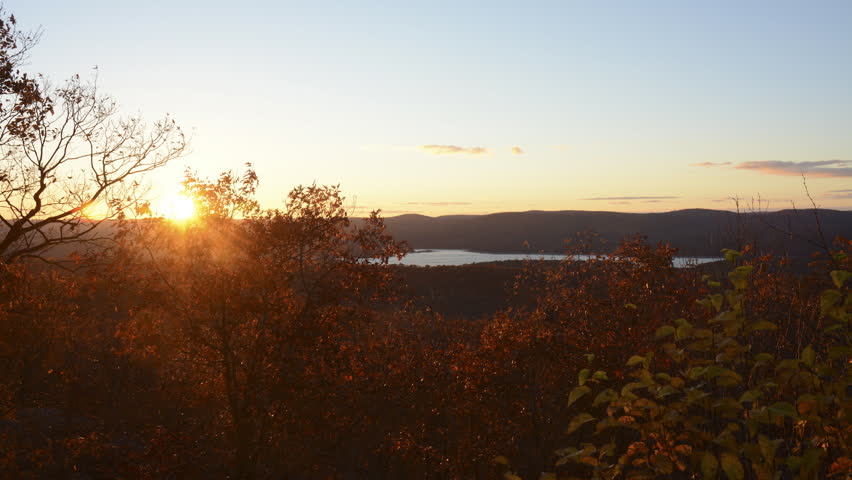 Autumn sunset over mountains with lake, sky, clouds and colorful trees in foreground. HD 1080 version.