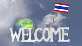 The word WELCOME in front of a turning globe and moving clouds in a blue sky with tooth pick and a small paper flag of THAILAND