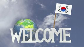 The word WELCOME in front of a turning globe and moving clouds in a blue sky with tooth pick and a small paper flag of SOUTH KOREA