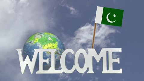 The word WELCOME in front of a turning globe and moving clouds in a blue sky with tooth pick and a small paper flag of PAKISTAN