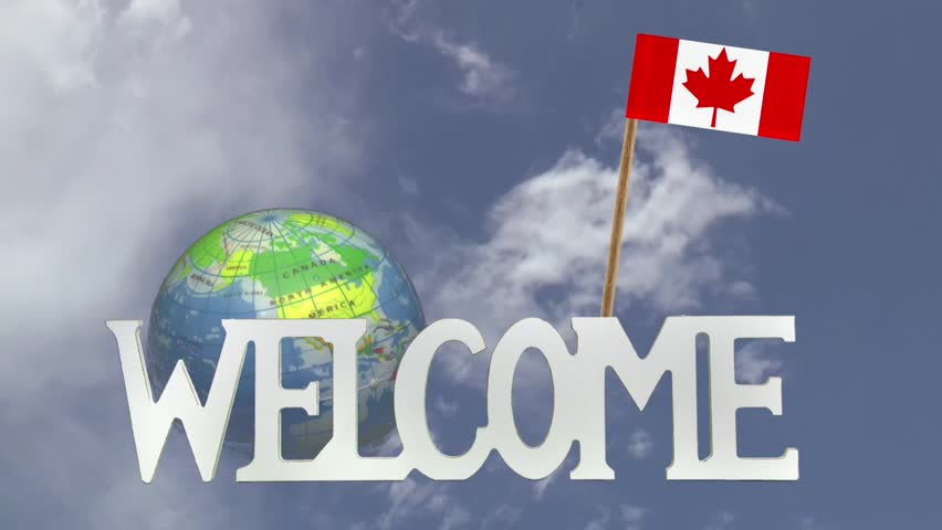 The word WELCOME in front of a turning globe and moving clouds in a blue sky with tooth pick and a small paper flag of CANADA