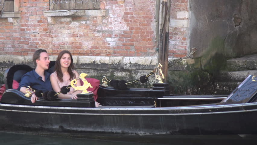 A young couple in love kiss on a gondola in Venice, Italy - in slow motion
